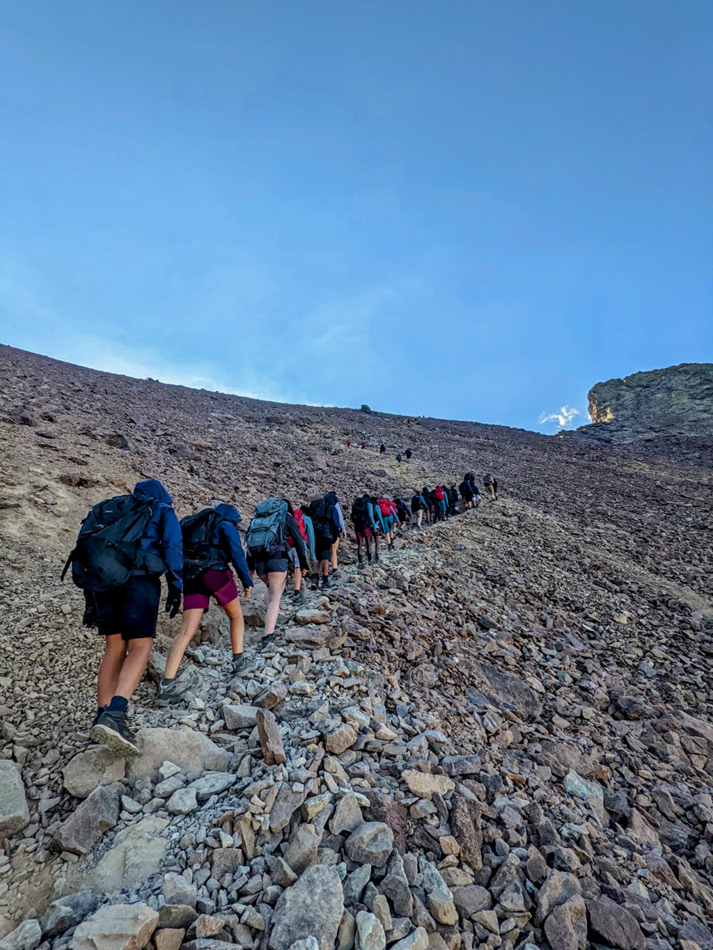 Les élèves de Saint-Denis et de Cannes-La Bocca progressent sur les sentiers du Monte Cinto au lever du jour, guidés par leurs accompagnateurs.