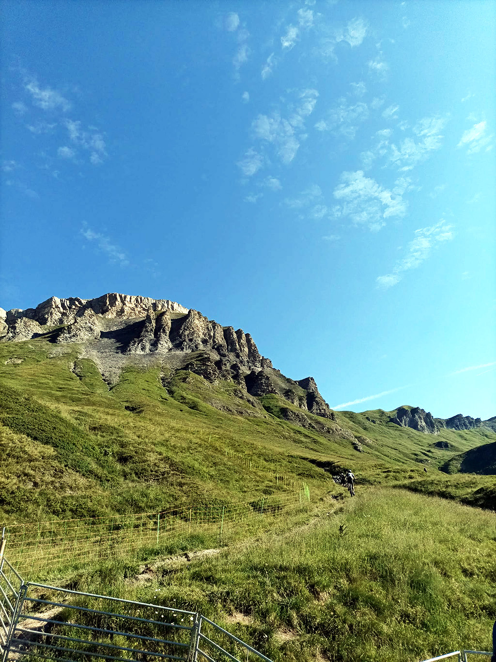 Des jeunes suivis par la PJJ croisent des cyclistes sur une piste aménagée avec une barrière lors de leur randonnée dans les Alpes.