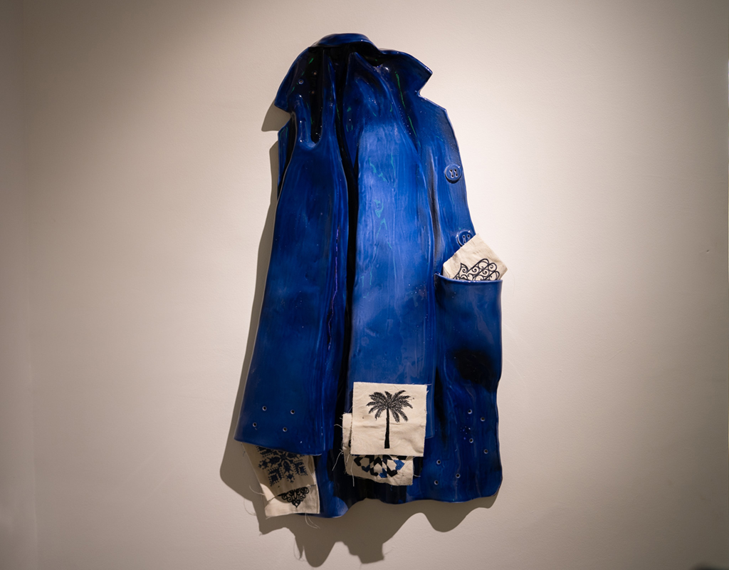 L’uniforme, céramique sculptée à la main, émail bleu, broderie machine, 2023–2024 — Exposition Cosmogrammes de Sara Ouhaddou, Institut des Cultures d’Islam, Paris, 2025. Crédit photo : DR.