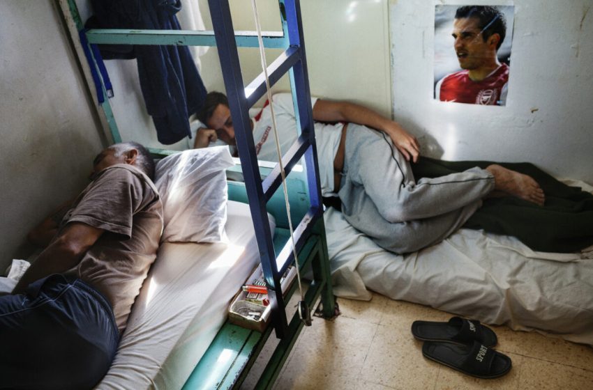Intérieur d’une cellule d’un centre pénitentiaire avec plusieurs couchages dans un espace restreint.