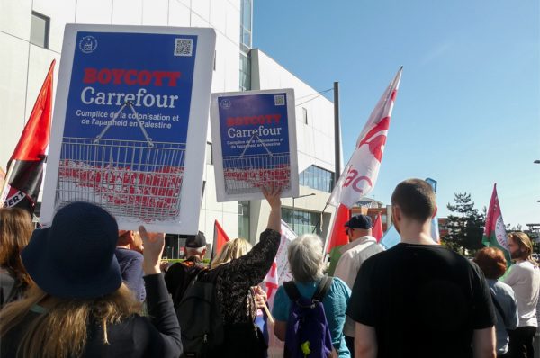 Militants propalestiniens rassemblés devant le siège de Carrefour à Massy, le 22 mai 2026, brandissant pancartes et slogans dénonçant l’implantation de franchises dans les colonies israéliennes et le partenariat avec l’État israélien.