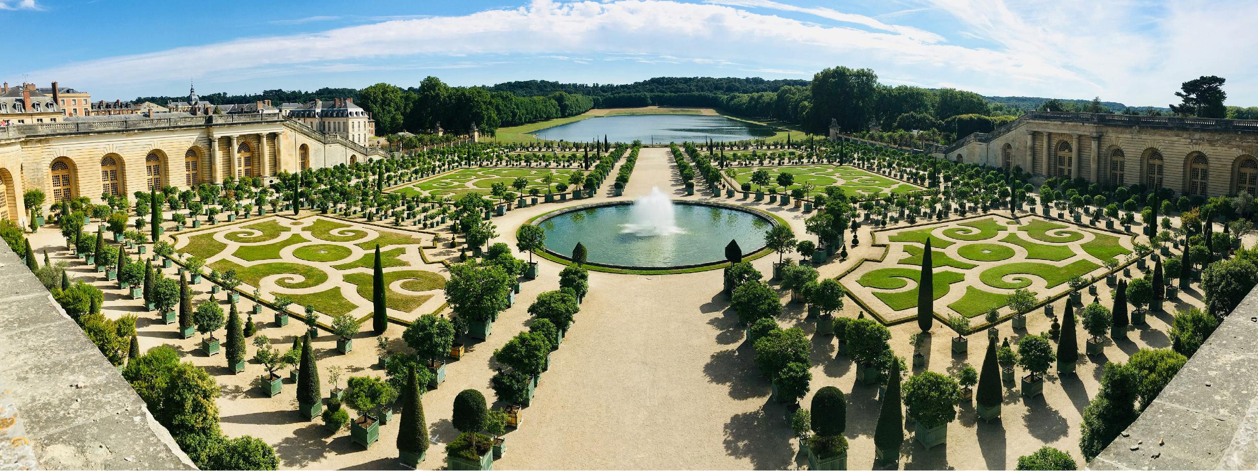 VersaillesVue panoramique des jardins du château de Versailles avec bassin central et parterres à la française.