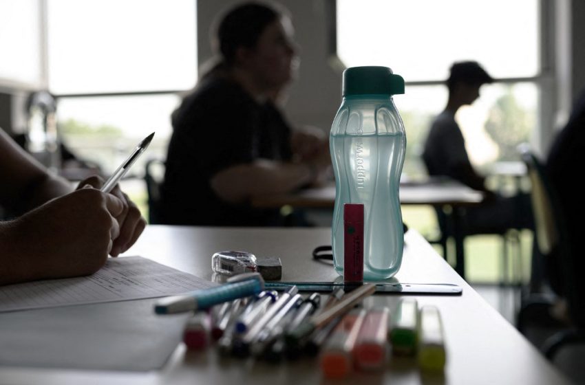 Élève se préparant pour une épreuve du baccalauréat, bouteille d’eau sur la table, en période de canicule.