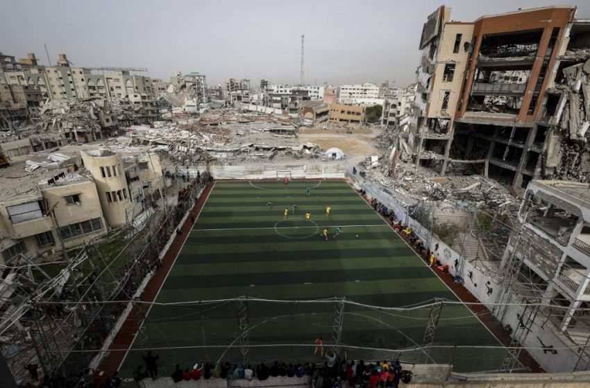 Footballeurs sur un terrain de Gaza au milieu d’un paysage dévasté