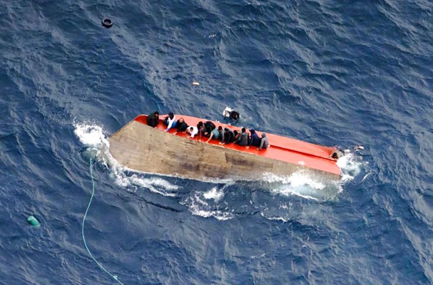 Des migrants assis sur une embarcation chavirée au large de la Libye.